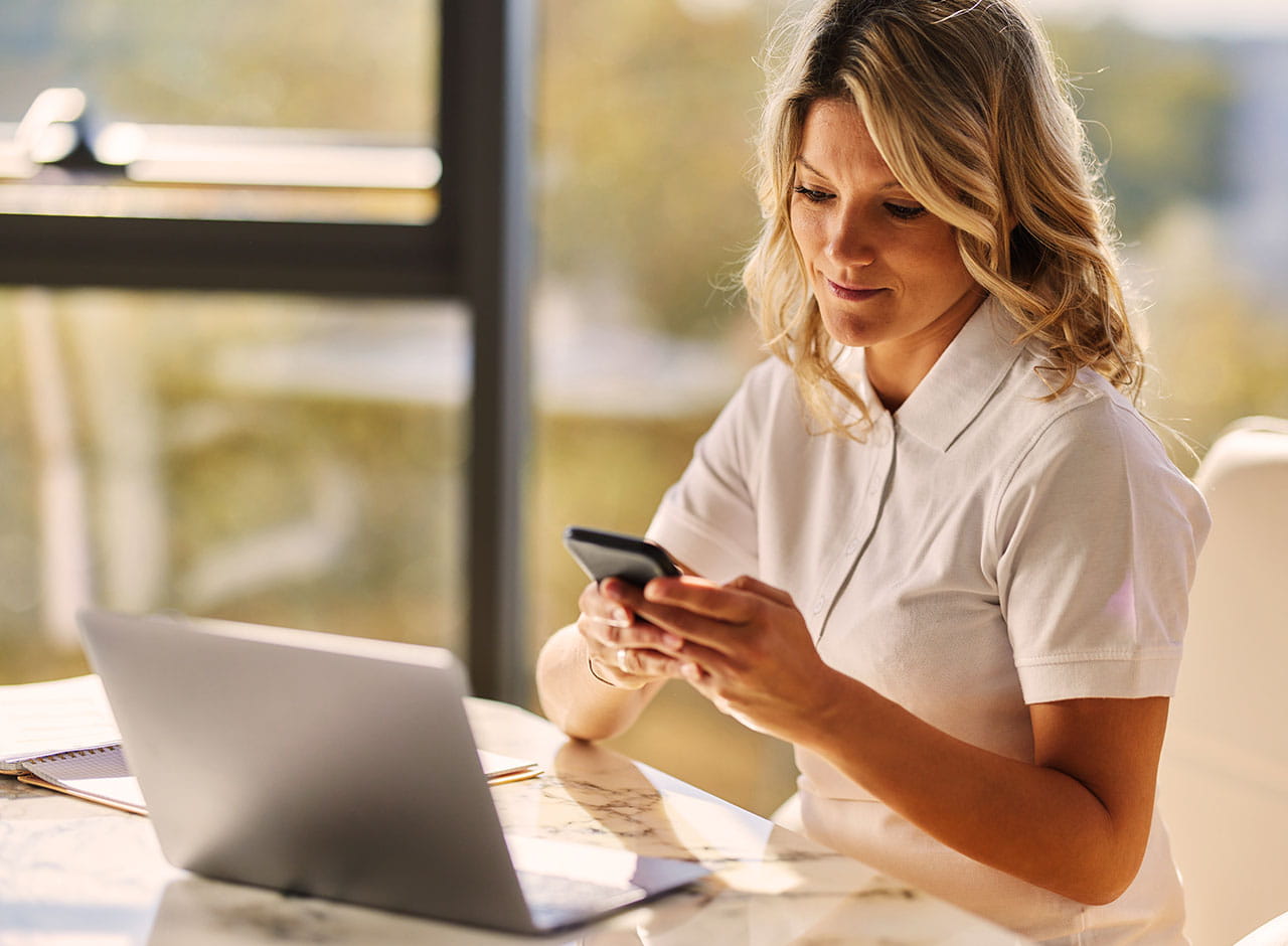 Kvinde bruger mobil og computer i forbindelse med bolig og rådgivning