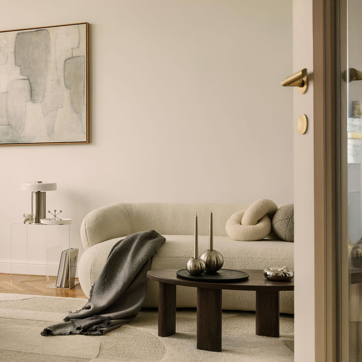 Lys og minimalistisk stue med skandinavisk indretning, bouclé sofa, loungestol i tekstil og neutrale farver med kunst på væggen