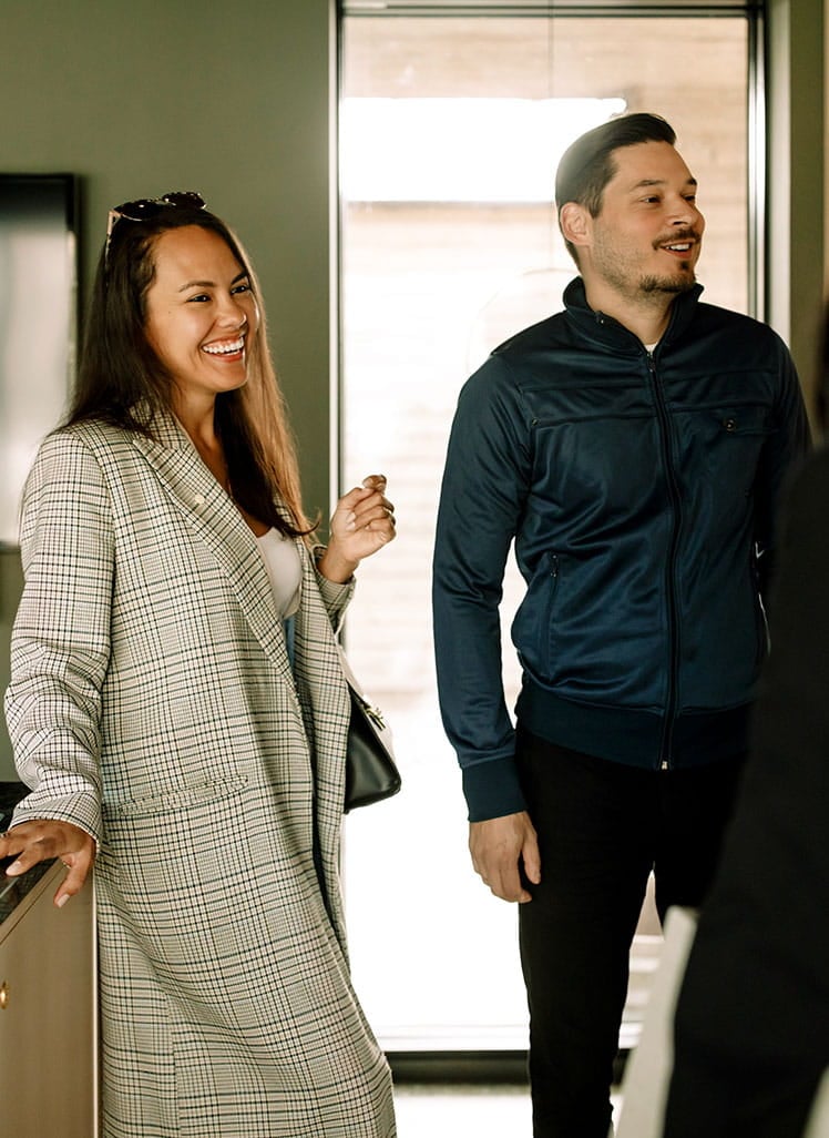 Par står i et køkken og taler med en ejendomsmægler