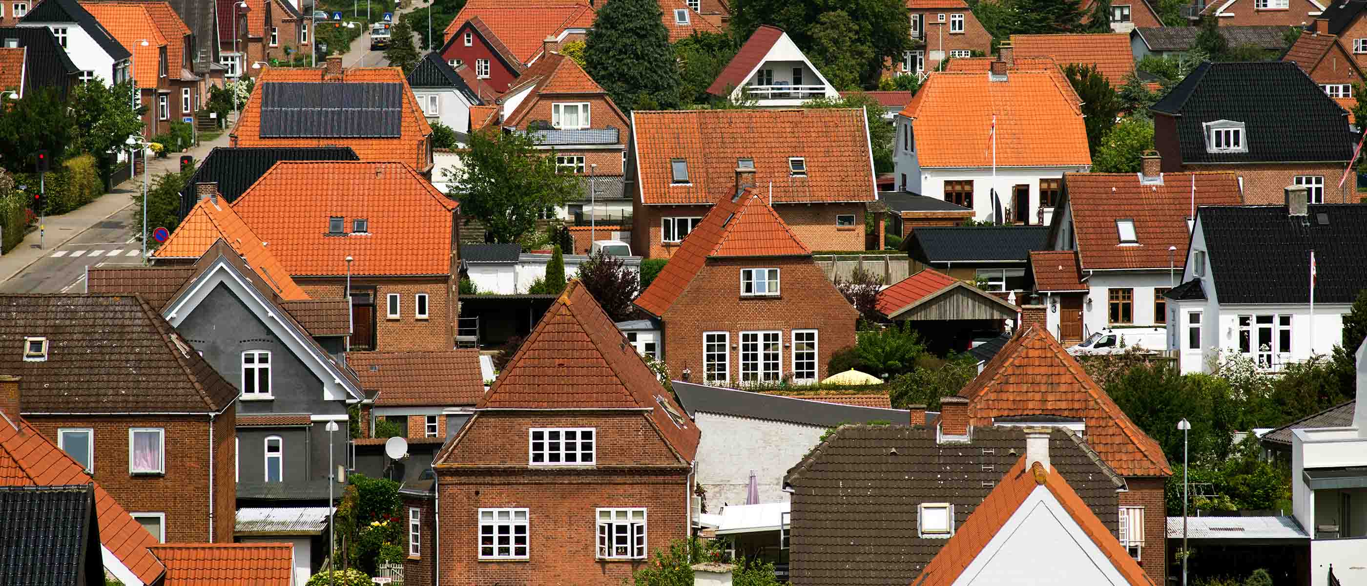 Dansk parcelhuskvarter med enfamiliehuse og røde tegltage set fra oven