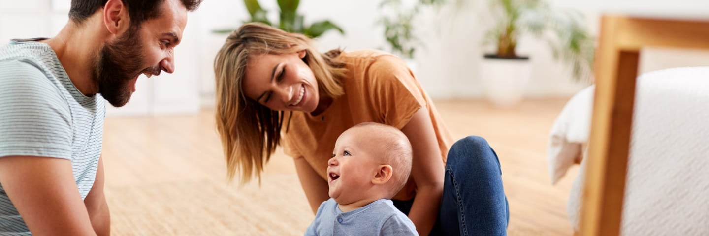 Far, mor og baby leger på gulvet