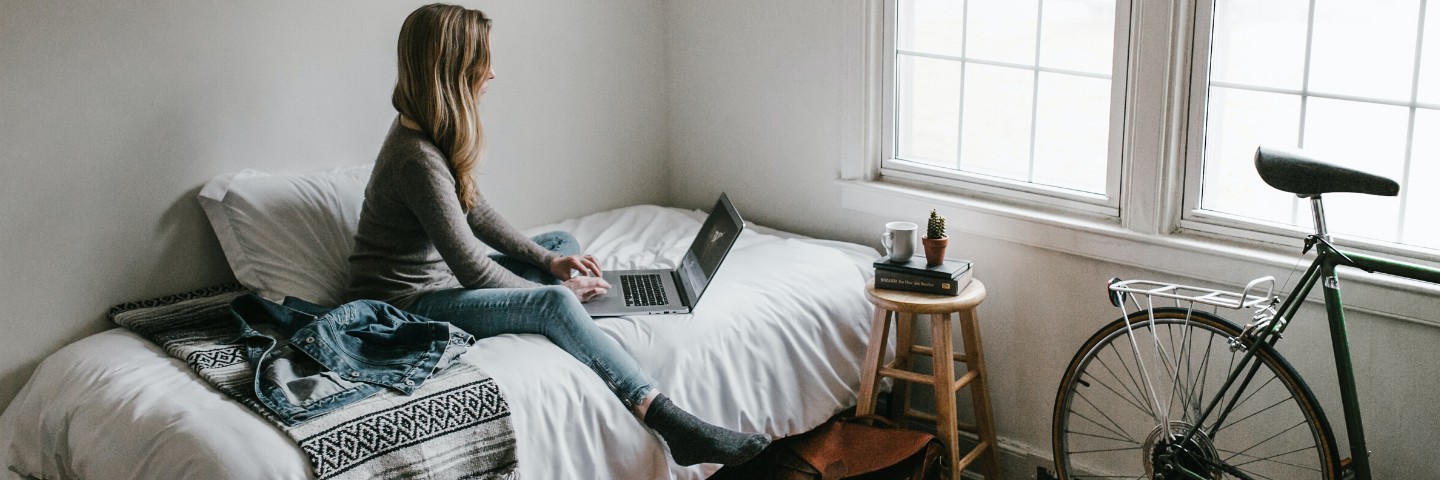 Pige sidder på seng med computer